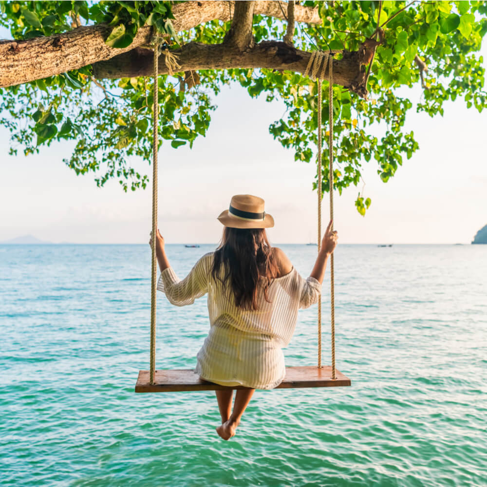 Traveler woman relaxing on swing above Andaman sea Railay beach